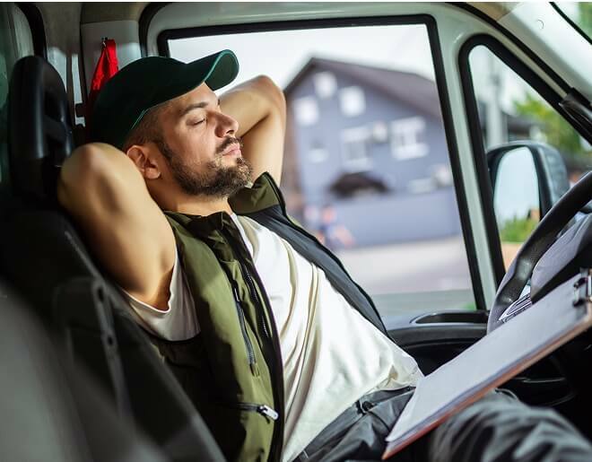 Worker relaxing in drivers seat of parked service van