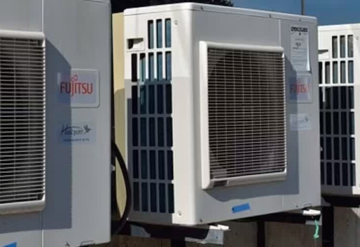 Outdoor air conditioning units mounted on a building exterior. The units are labeled "Fujitsu" with grills and cables visible.