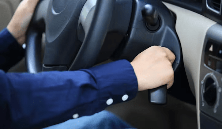 A person wearing a blue shirt is inserting a key into the ignition of a car.