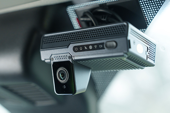 A black dash cam mounted to a vehicle's windshield, shown from a slightly low angle.