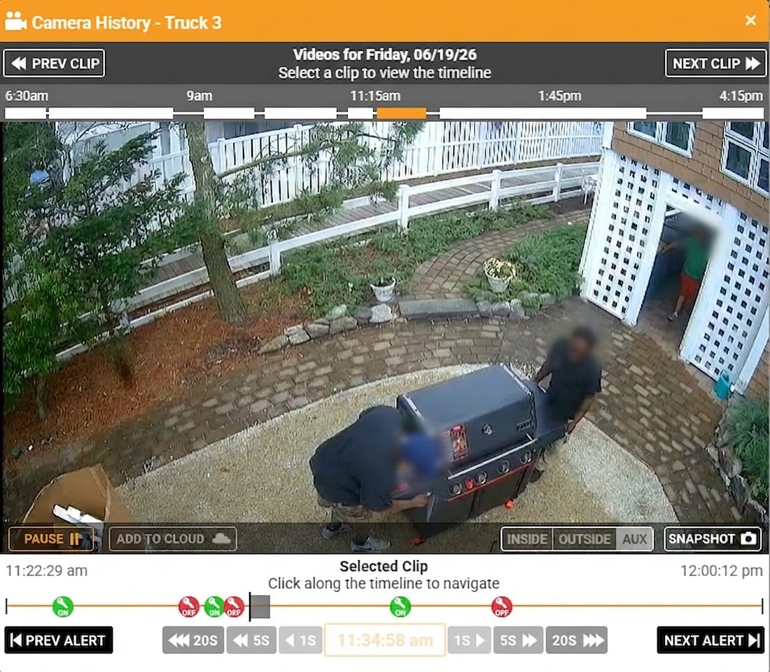 A surveillance camera interface showing two people moving a grill on a patio, with a timeline at the bottom for video navigation.