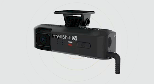 A black IntelliShift dashcam with a small camera lens, an LED indicator, and a power connector, mounted on a vehicle windshield.